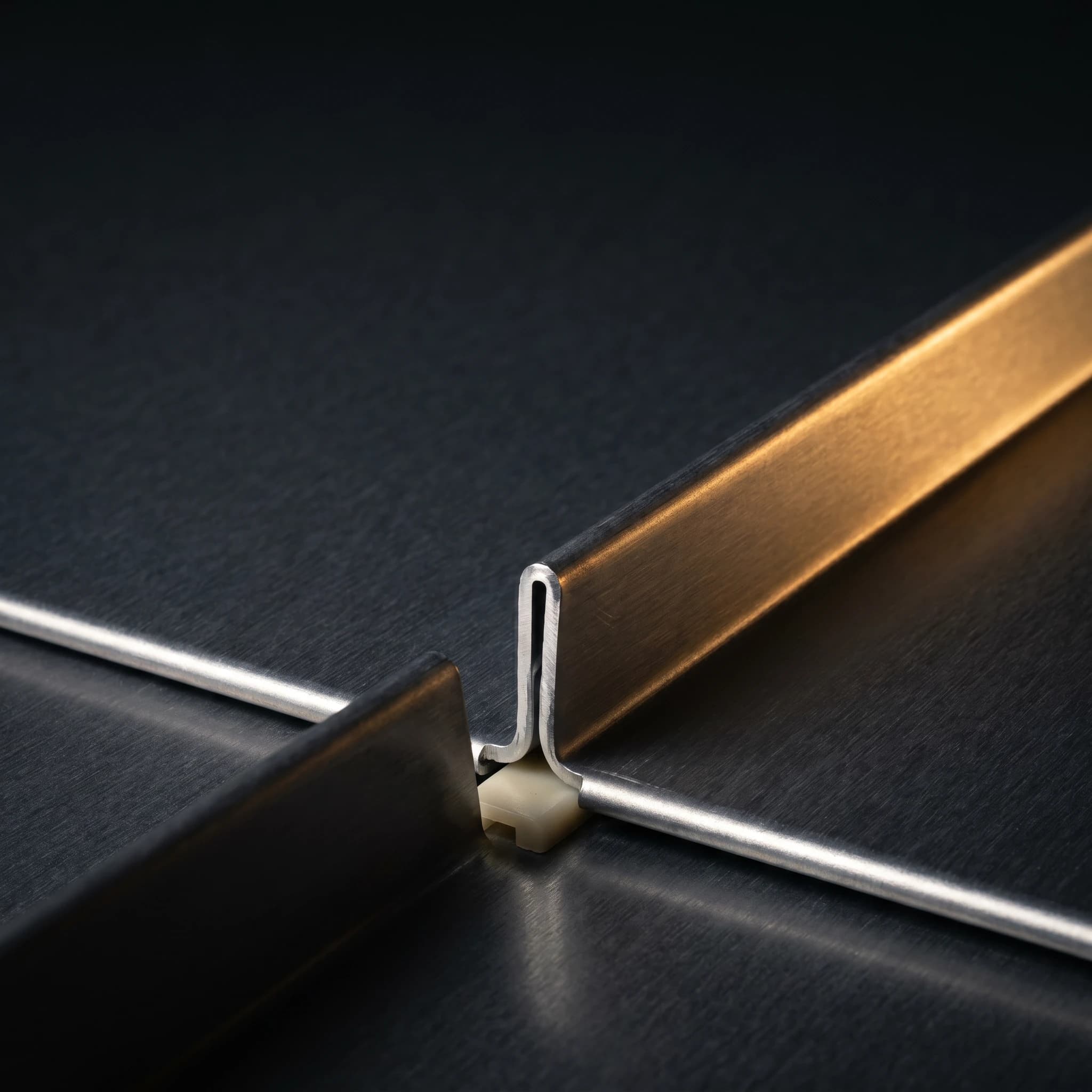 Macro photograph of two interlocked Riverclack panel edges held by a plastic clip, brass rim light on the seam ridge